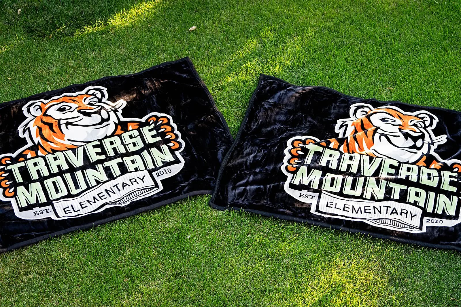 Two black-and-orange tiger blankets laid on grass with the mascot art printed crisp and full-bleed