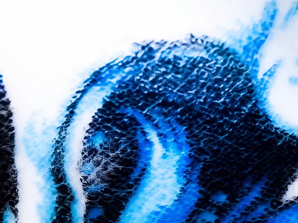 Thread-level macro where white blends into blue across dyed-through blanket fibers